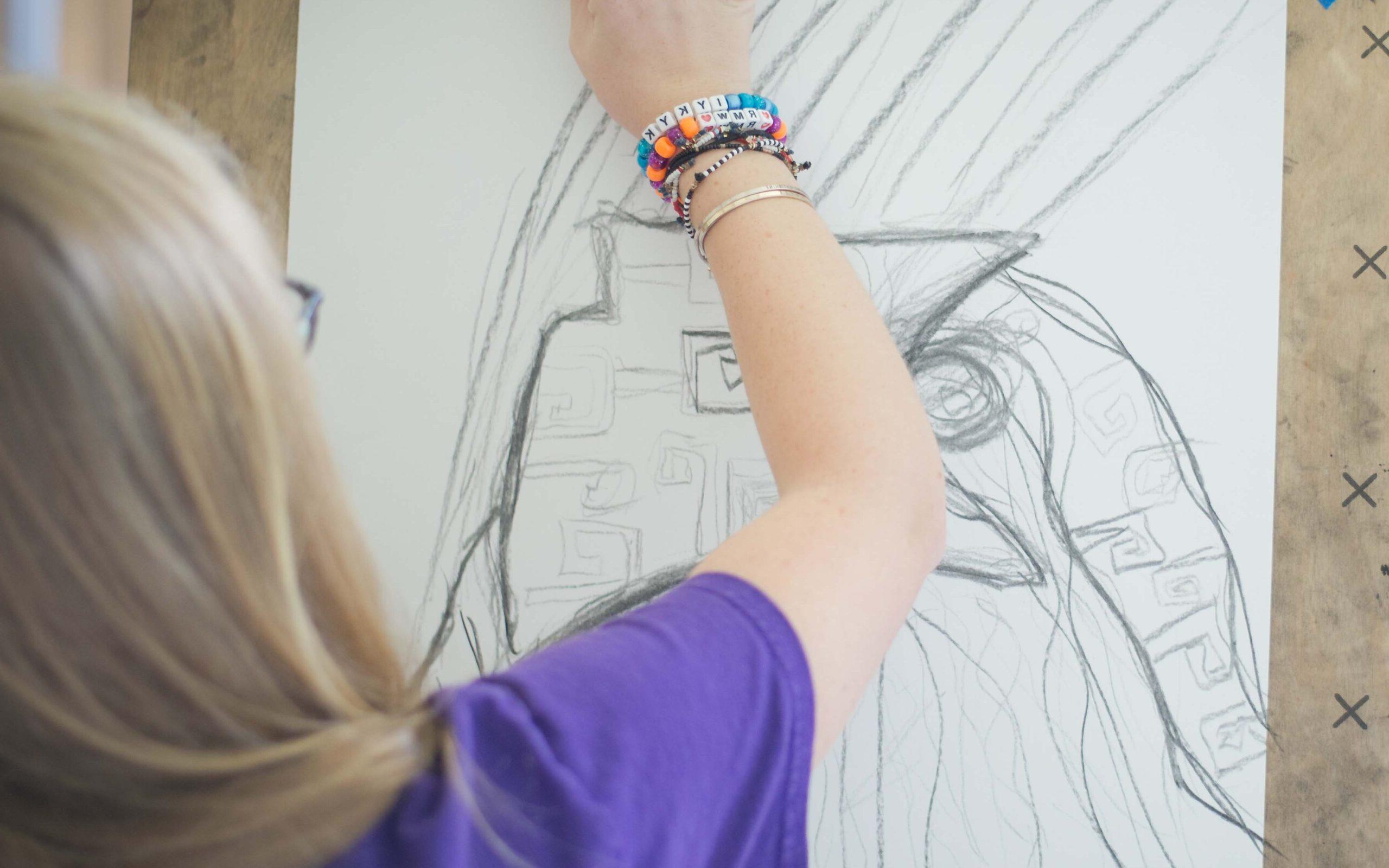 A student sketches on paper taped to an easel